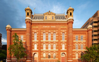 The front facade of the Planet Word building. It is a historic red brick building with decorative windows, cupolas, and a mansard roof.